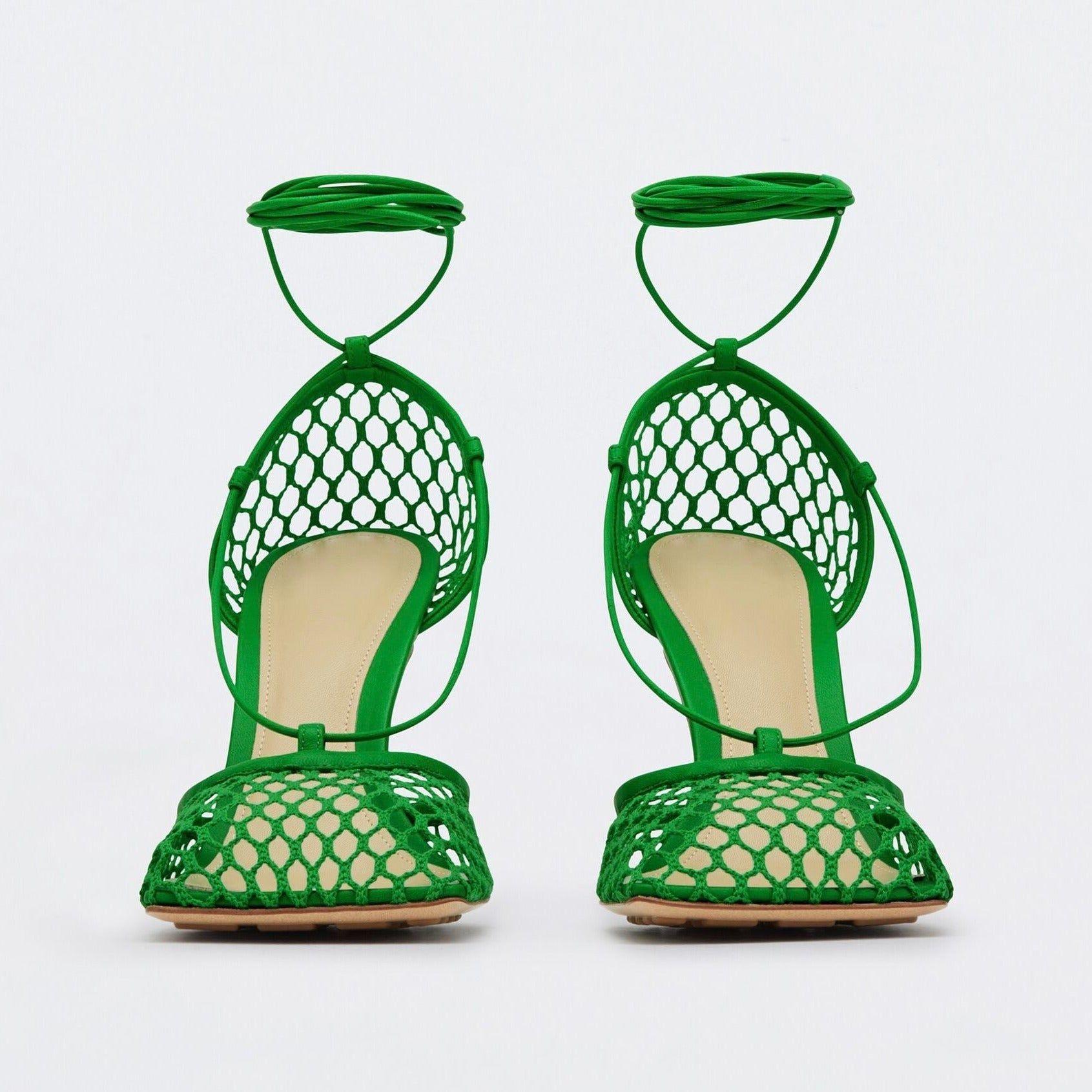 Pair of green lace-up high-heeled shoes on a white background