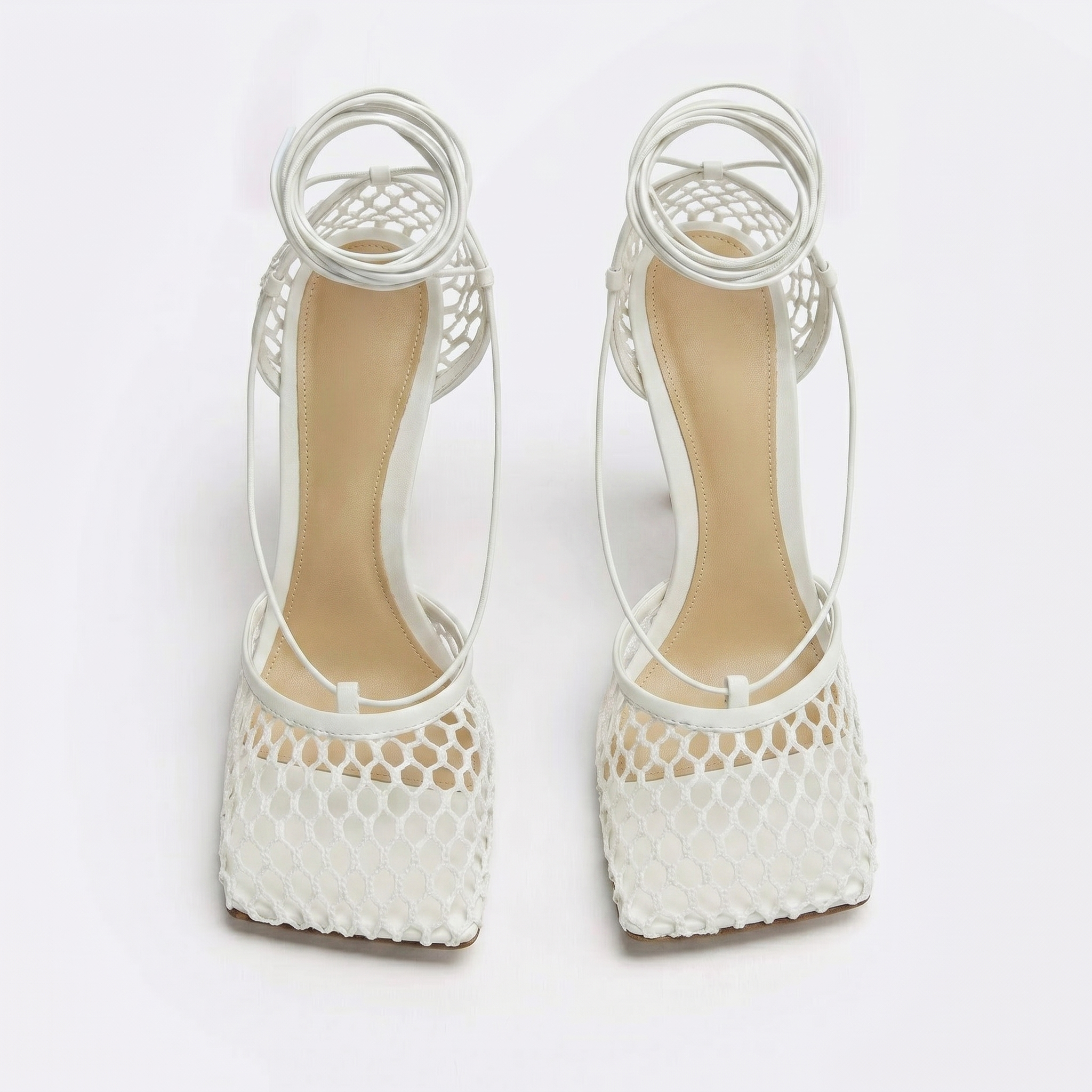 White high-heeled shoes with mesh design on a white background