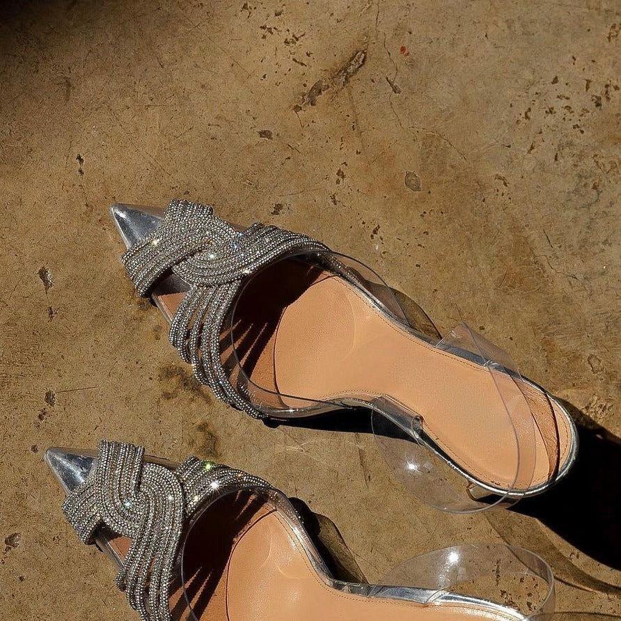 Pair of high-heeled shoes with decorative straps on a textured surface