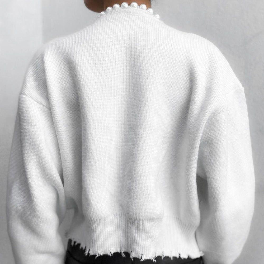 White sweater with pearl details on a plain background