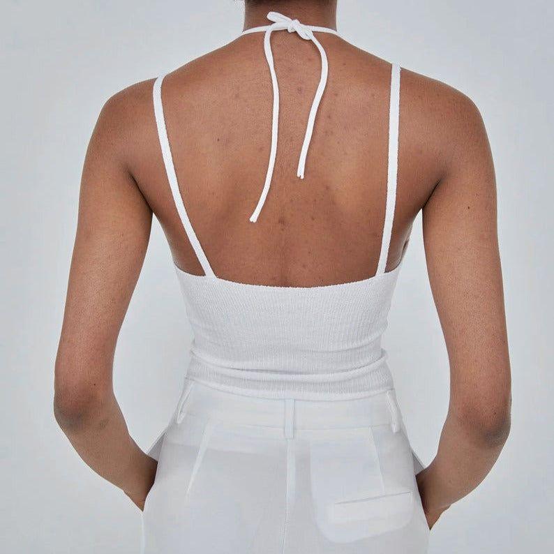 White sleeveless top with thin straps on a plain background