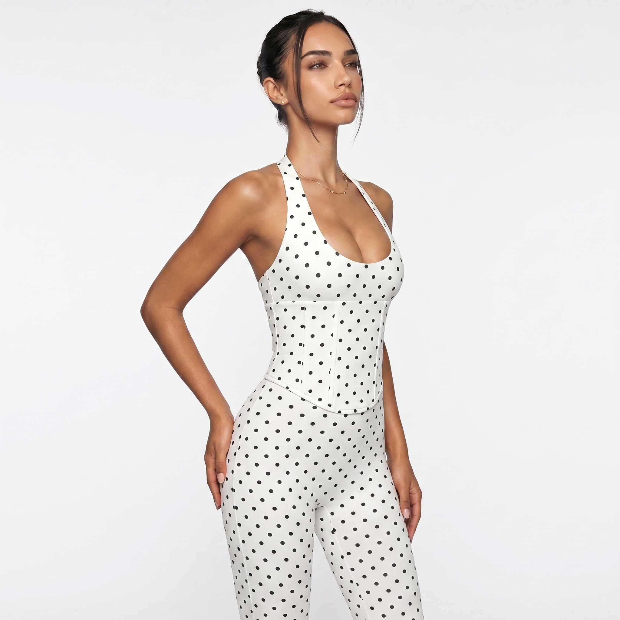 Woman wearing a white polka dot jumpsuit on a plain background