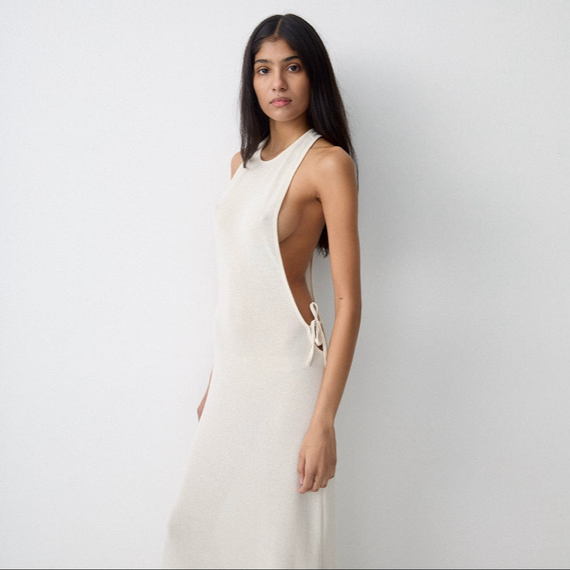 Woman wearing a white sleeveless dress against a plain background