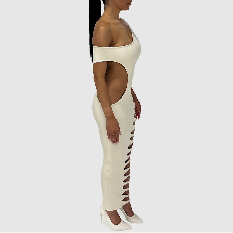 Woman wearing a white off-shoulder dress with cut-out sides on a plain background