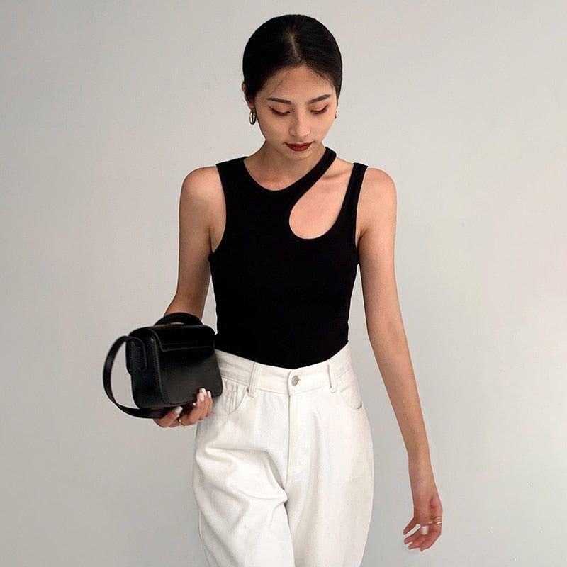 Woman holding a black handbag against a plain background