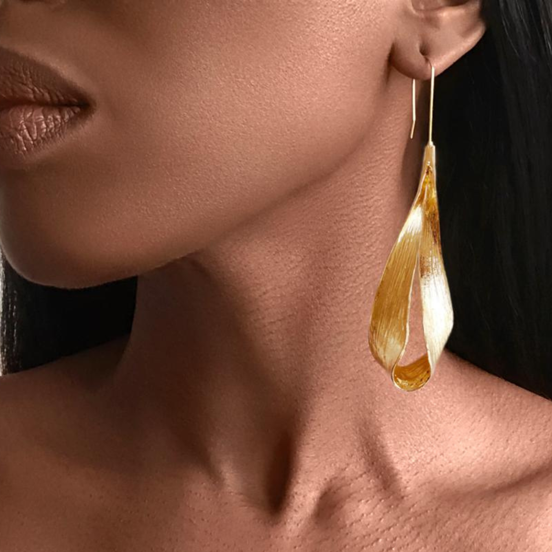 Close-up of a woman wearing a gold teardrop earring.