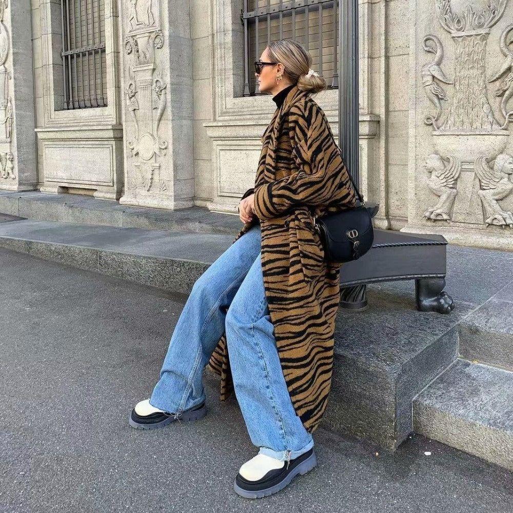 Person wearing a tiger-striped coat sitting on steps in an urban setting