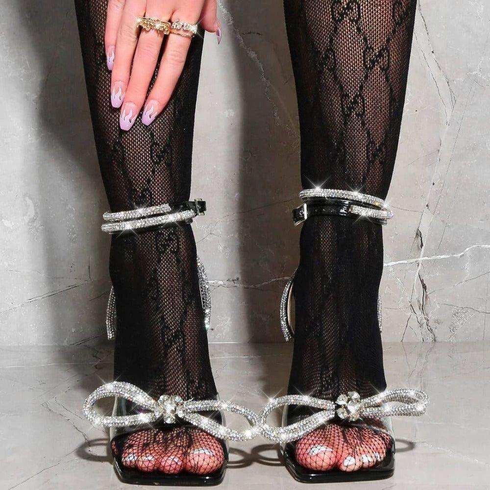 Black fishnet stockings with silver embellishments worn by a person on a light gray background