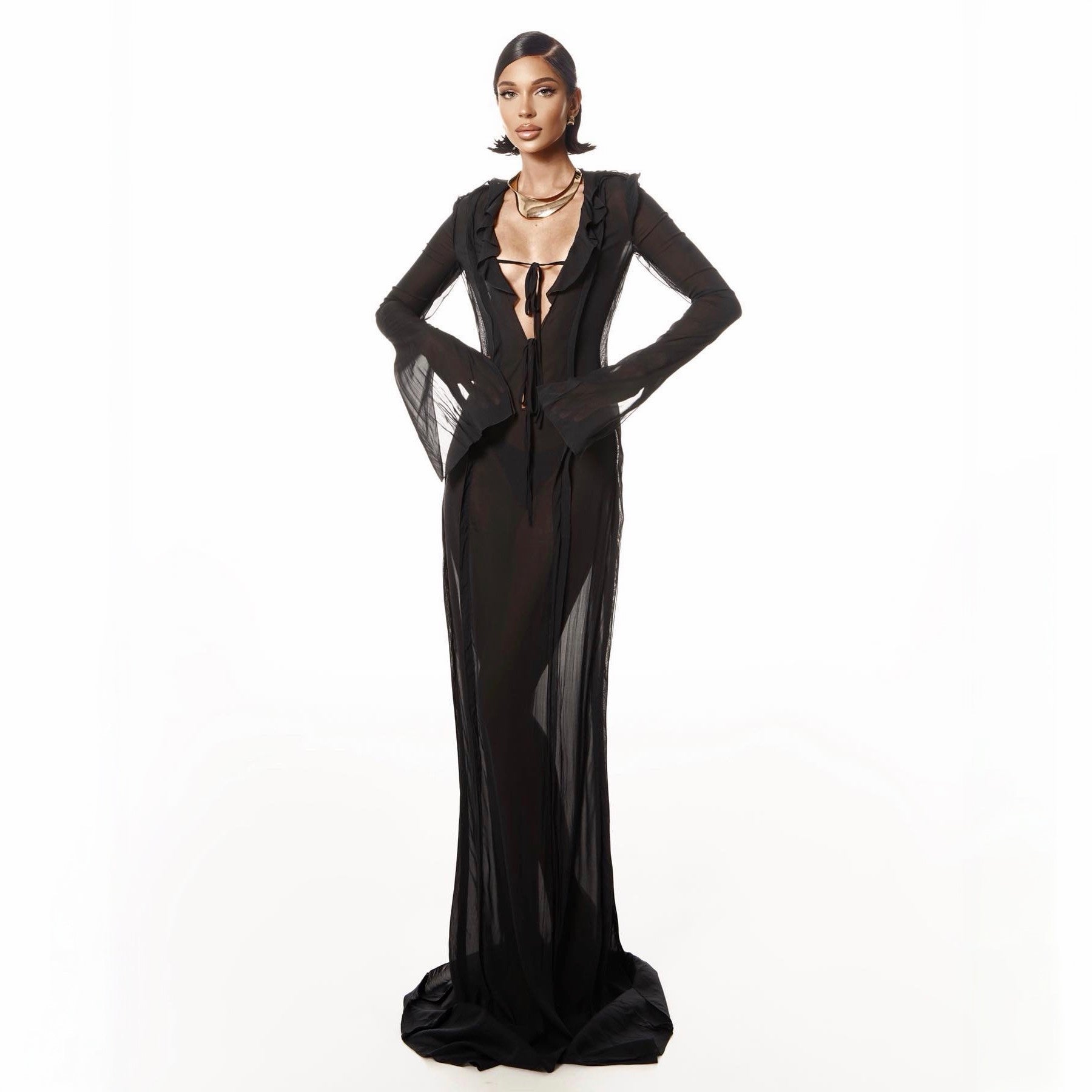 Woman wearing a black evening gown with sheer panels on a white background