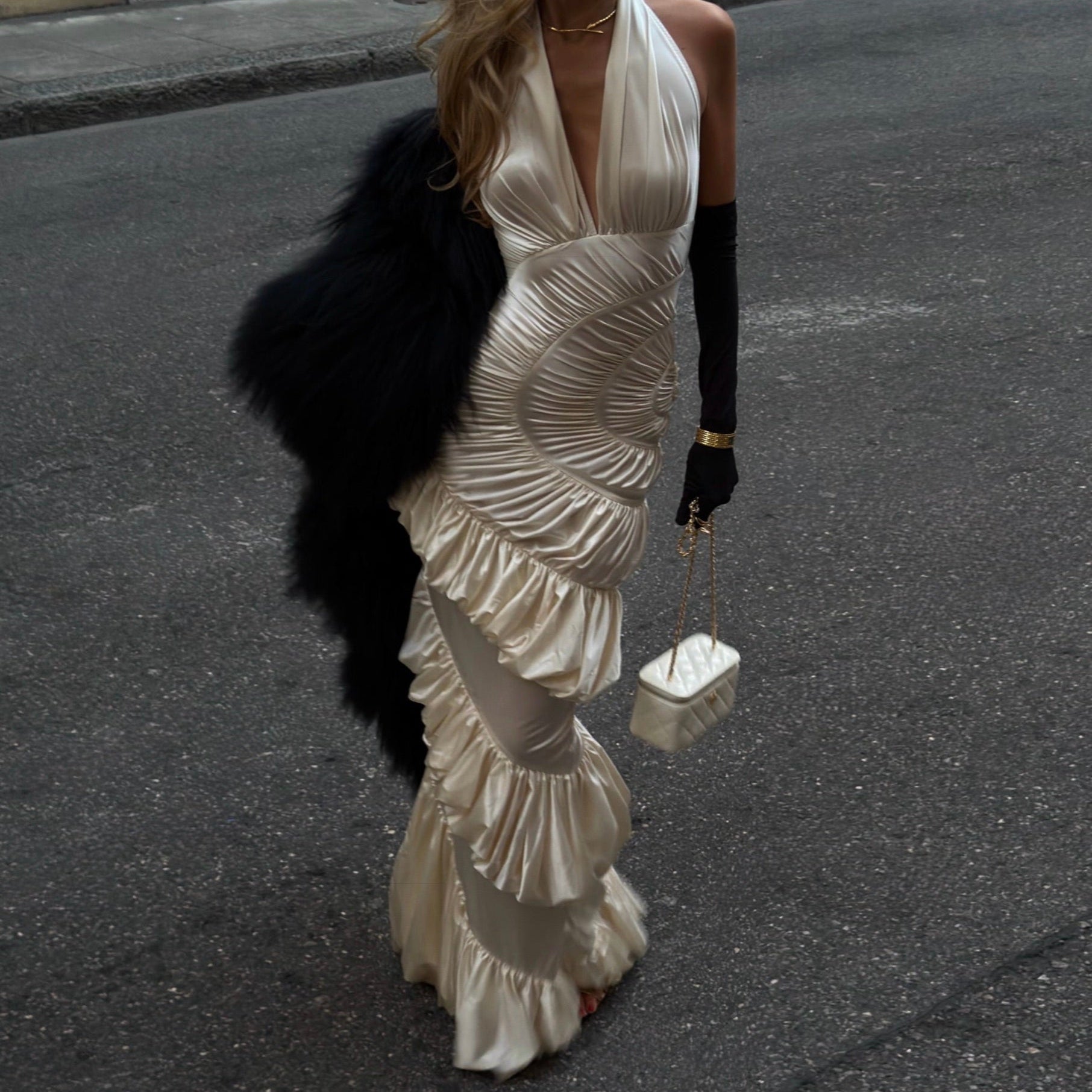 Woman in a white dress with ruffles walking on a street.