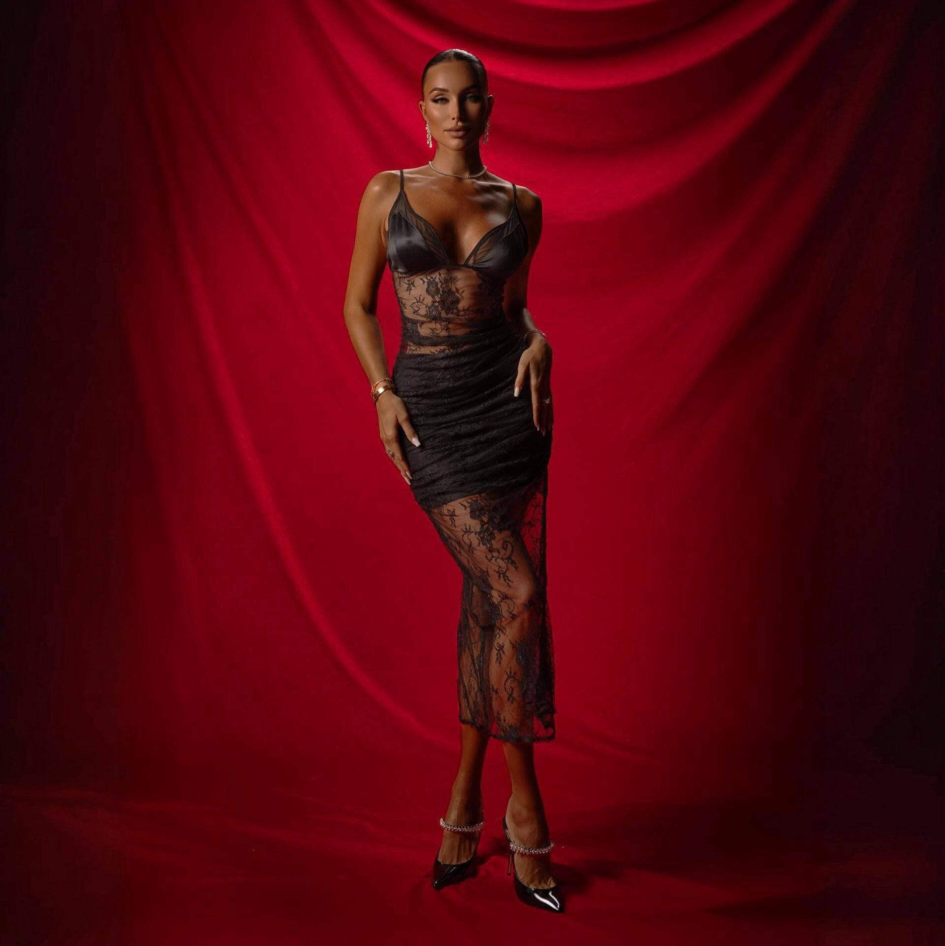 Woman wearing a black lace dress against a red curtain background
