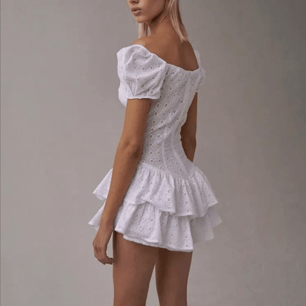 Woman wearing a white lace dress against a plain background