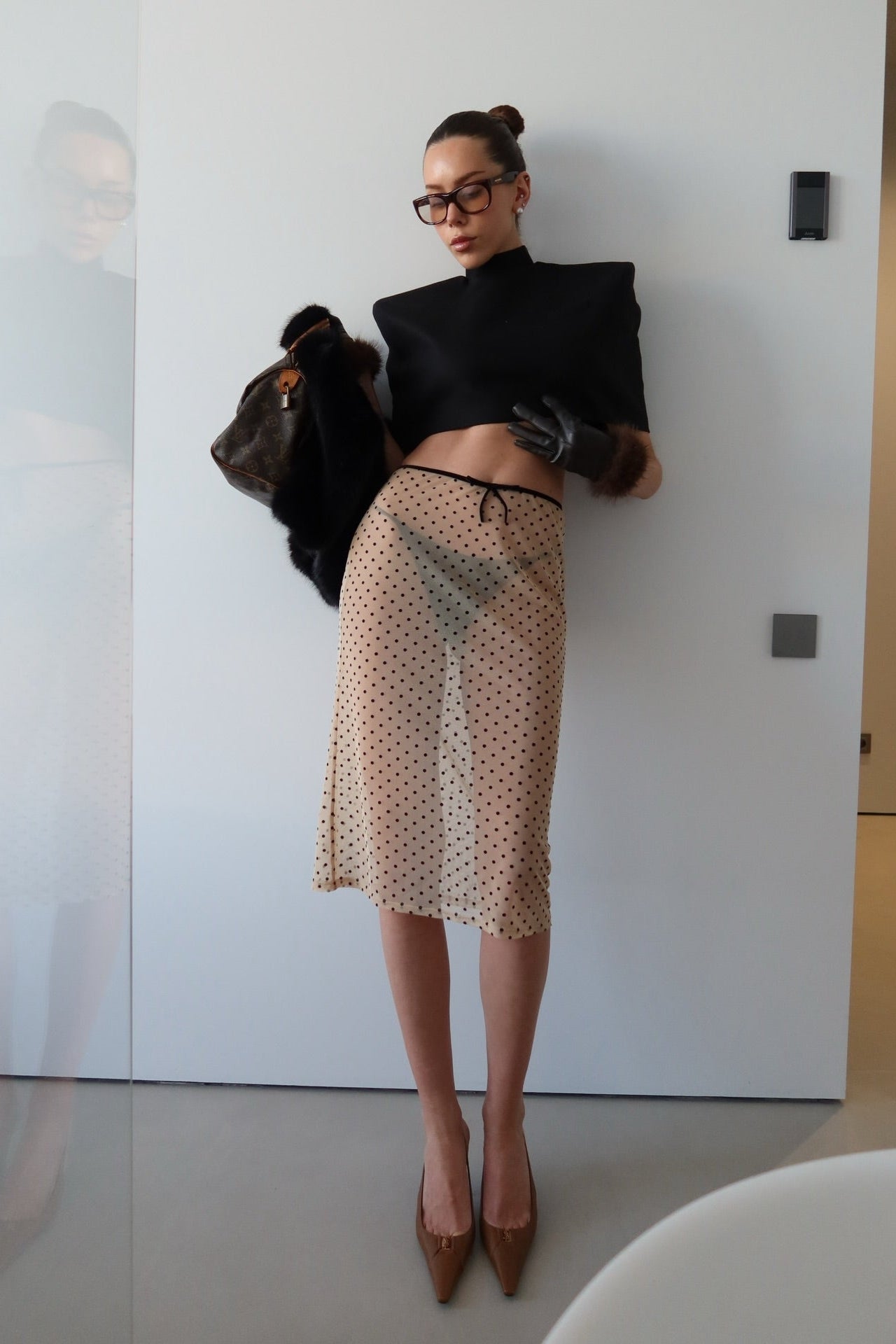 Full-length view of polka dot mesh midi skirt styled with black structured crop top and leather gloves