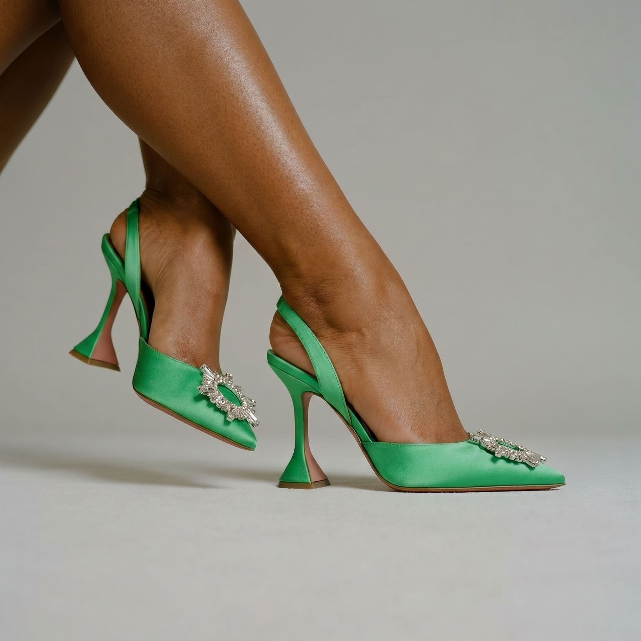 Green high-heeled shoes with embellishments on a neutral background