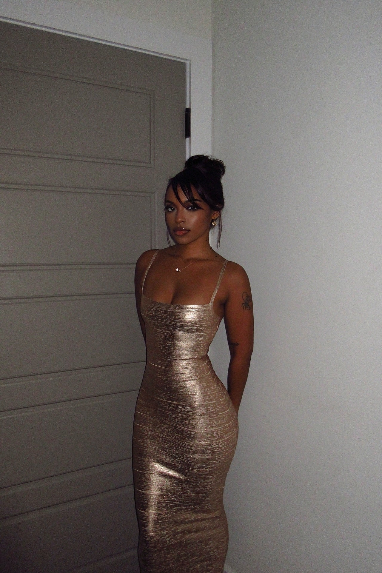 Model in gold metallic bandage maxi dress, full-length front view