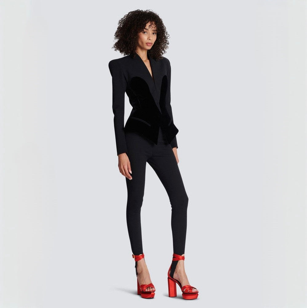 Woman wearing a black suit with red shoes on a light gray background