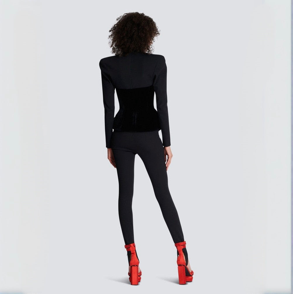 Person wearing a black outfit with red shoes on a light gray background