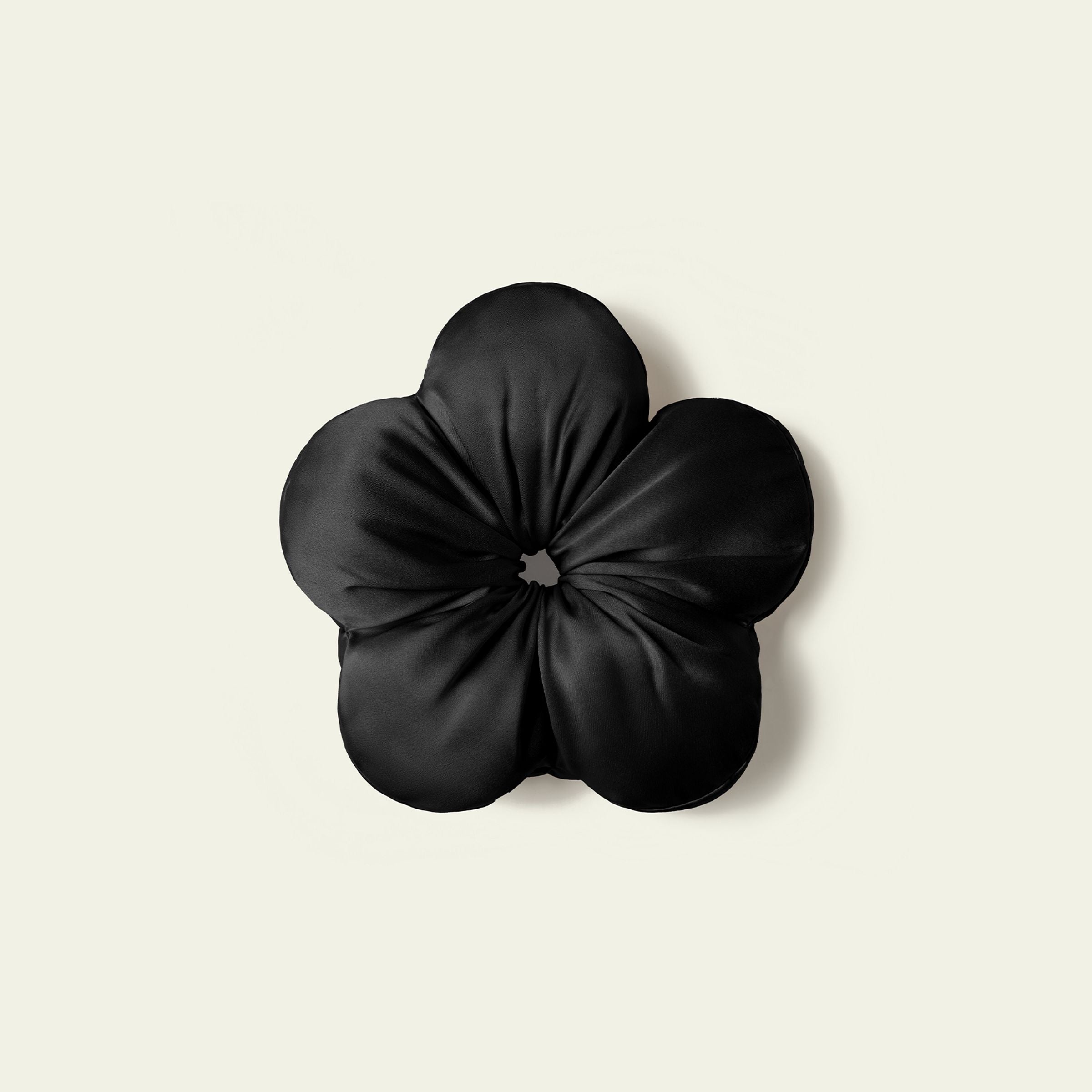 Black flower-shaped cushion on a beige background
