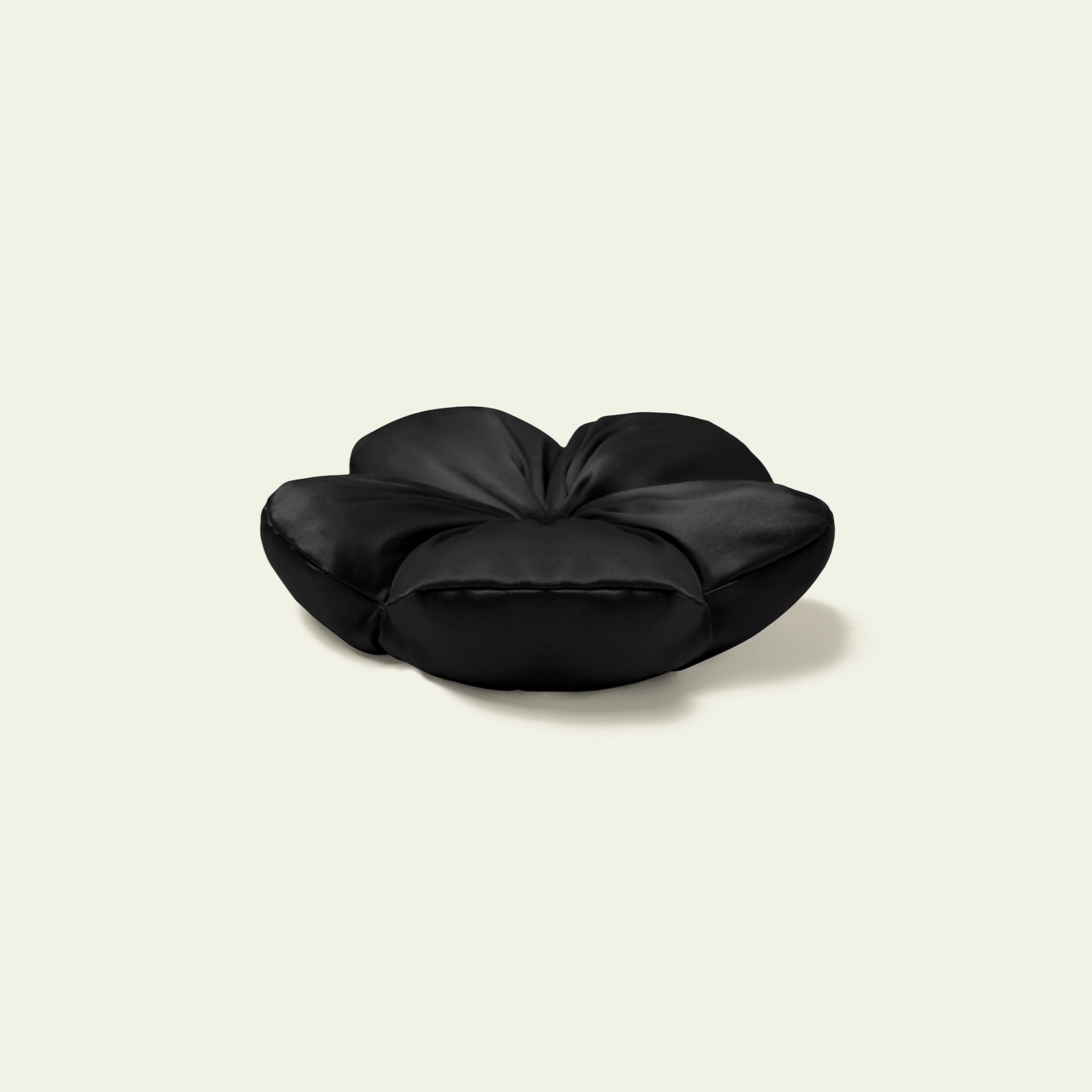Black flower-shaped pillow on a beige background