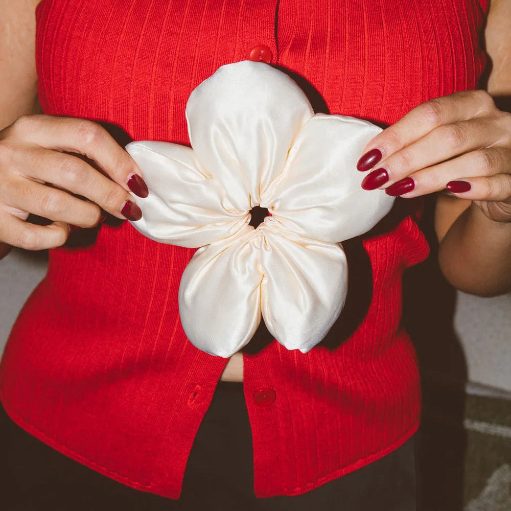 Person wearing a red top with a white flower accessory