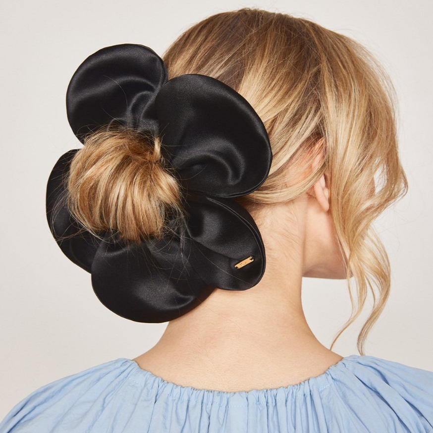 Black satin scrunchie holding a bun with a plain background