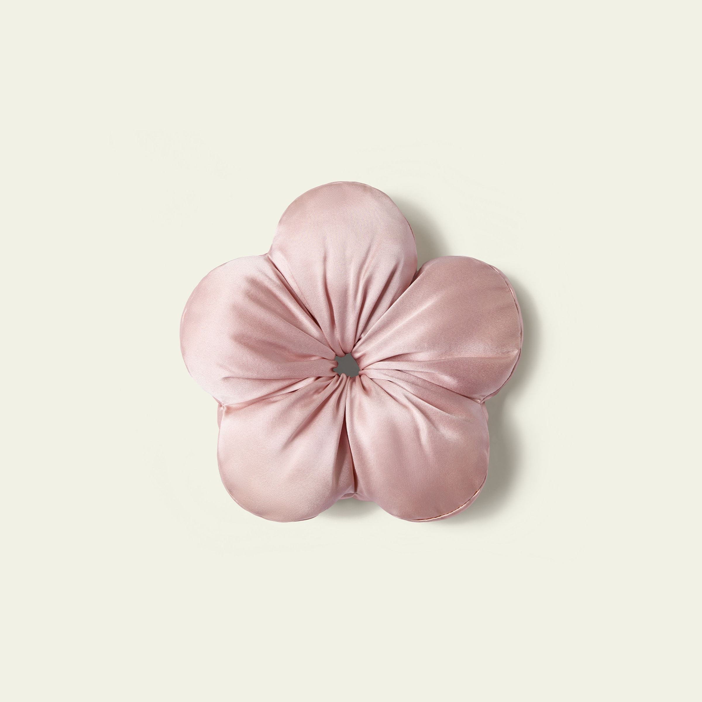 Pink flower-shaped cushion on a light beige background