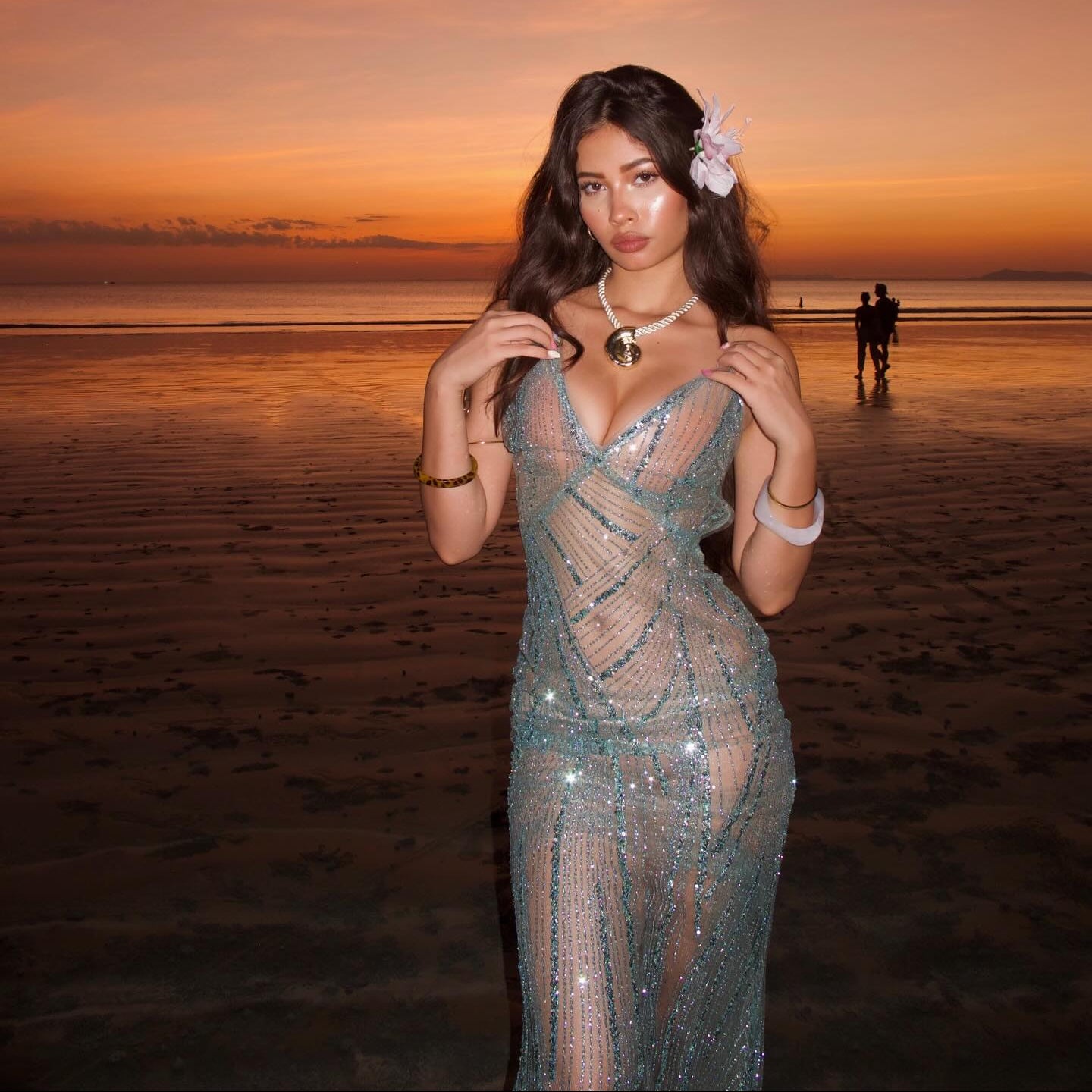 Woman in a sparkling dress on a beach at sunset