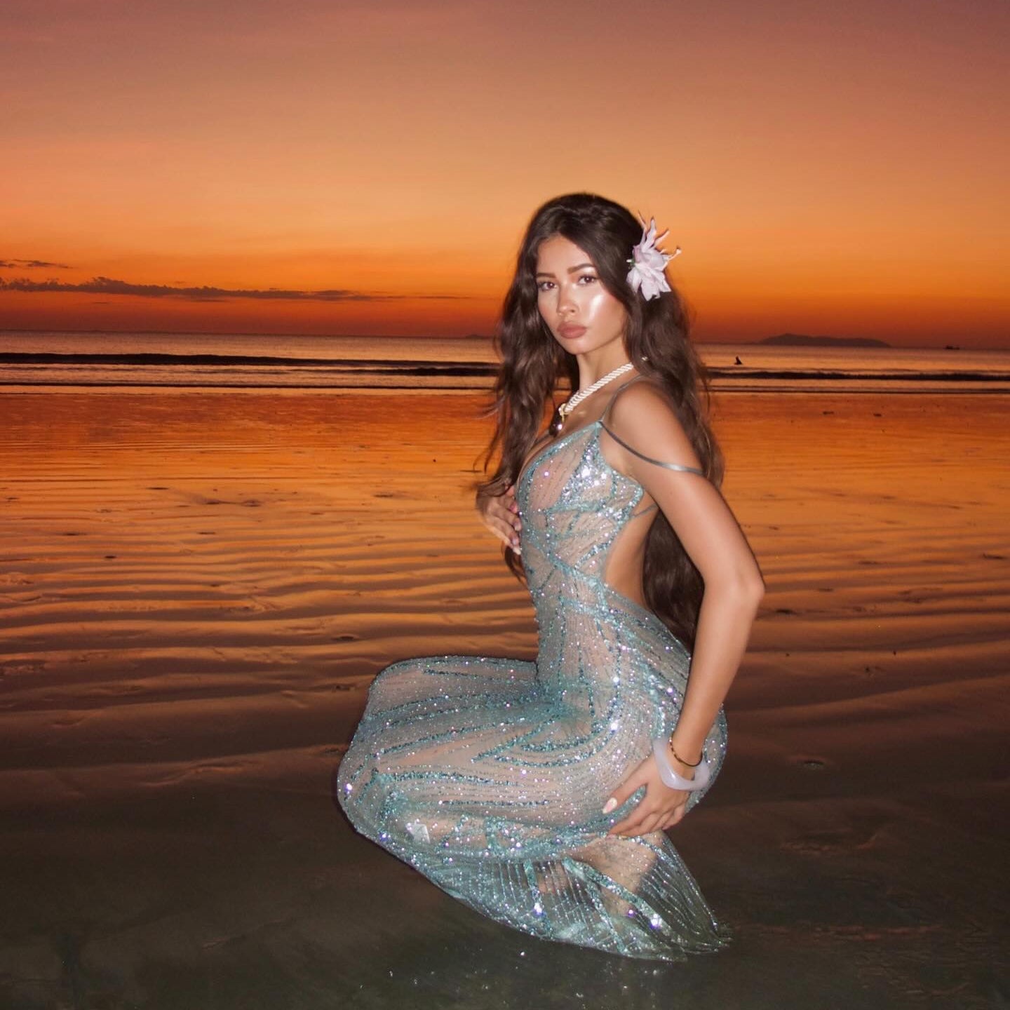Woman in a sparkly dress on a beach at sunset