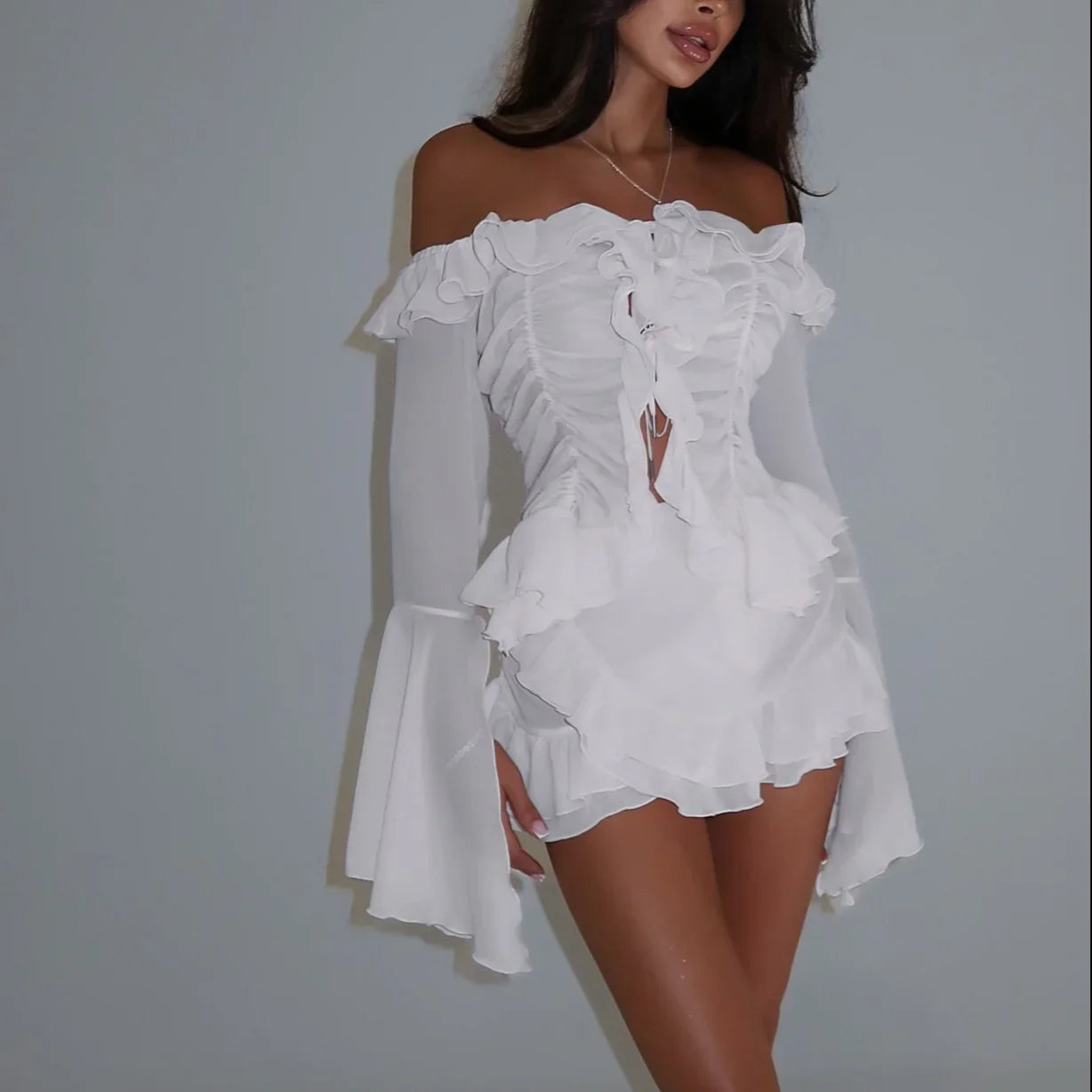 White off-shoulder dress with ruffled details on a plain background
