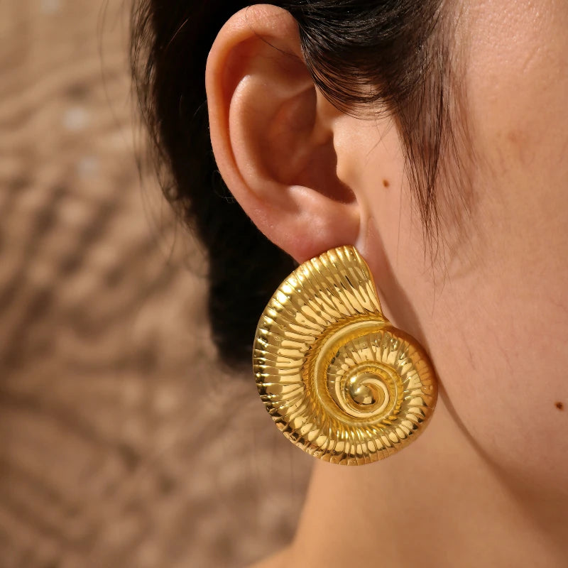 Gold spiral earring worn by a person with a blurred background