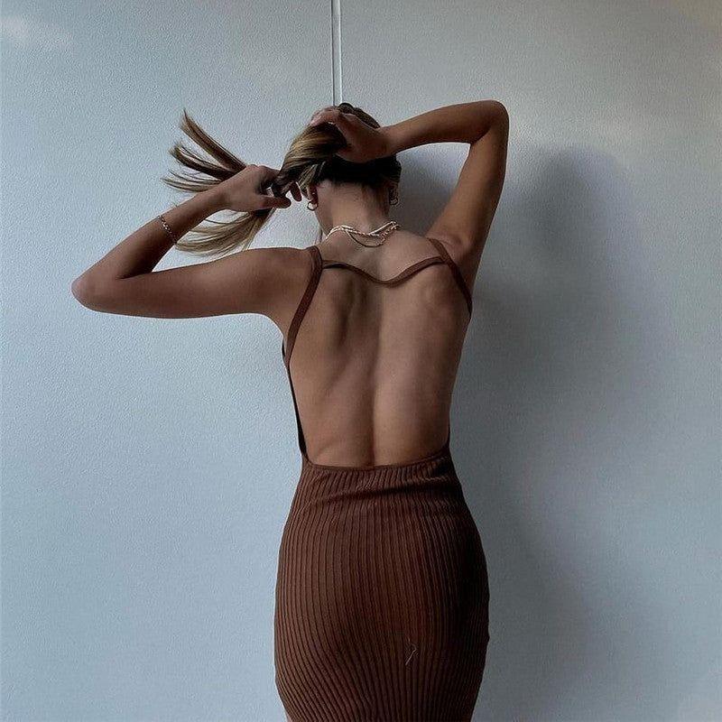 Woman in a brown ribbed dress standing against a light blue wall.