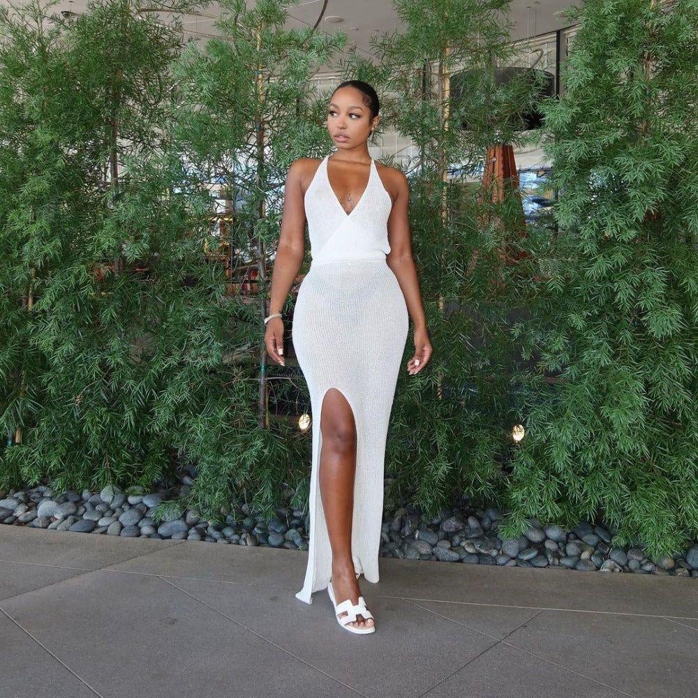 Woman in a white dress standing in front of greenery