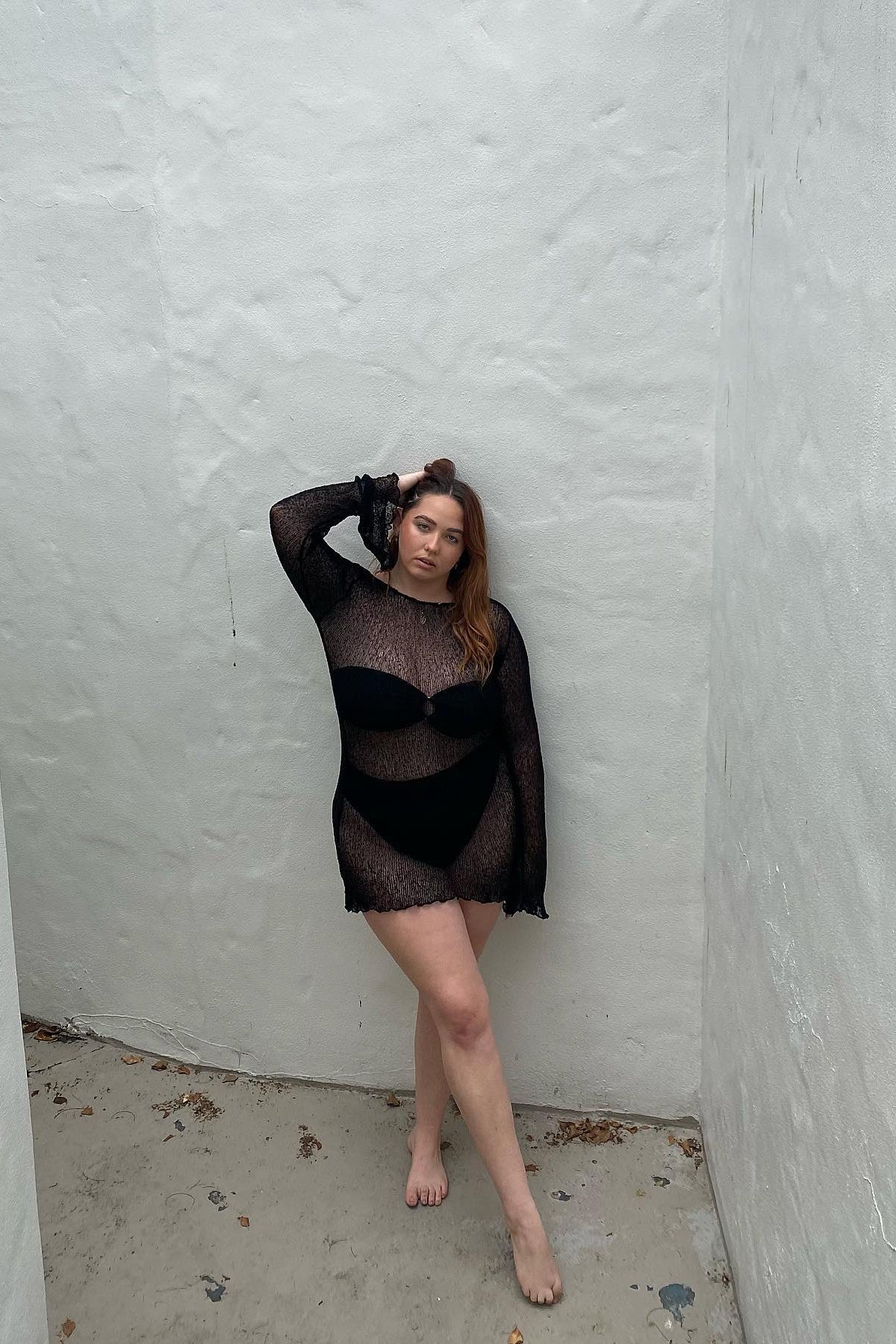 Sheer black beach mini dress with open back detail, sun-drenched setting