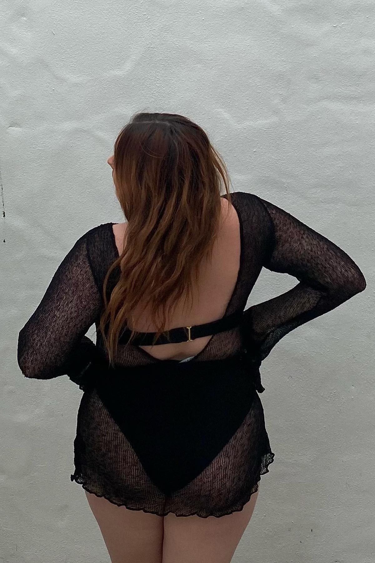 Semi-transparent black mini beach dress with dramatic back opening, model shot