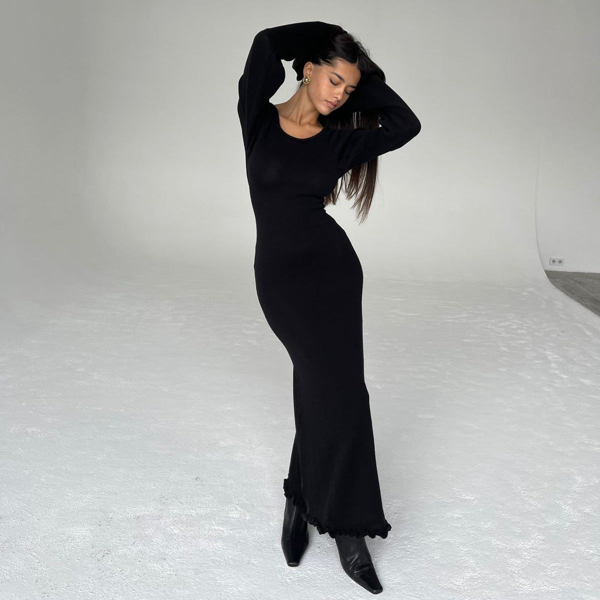 Woman in a black dress posing against a white background