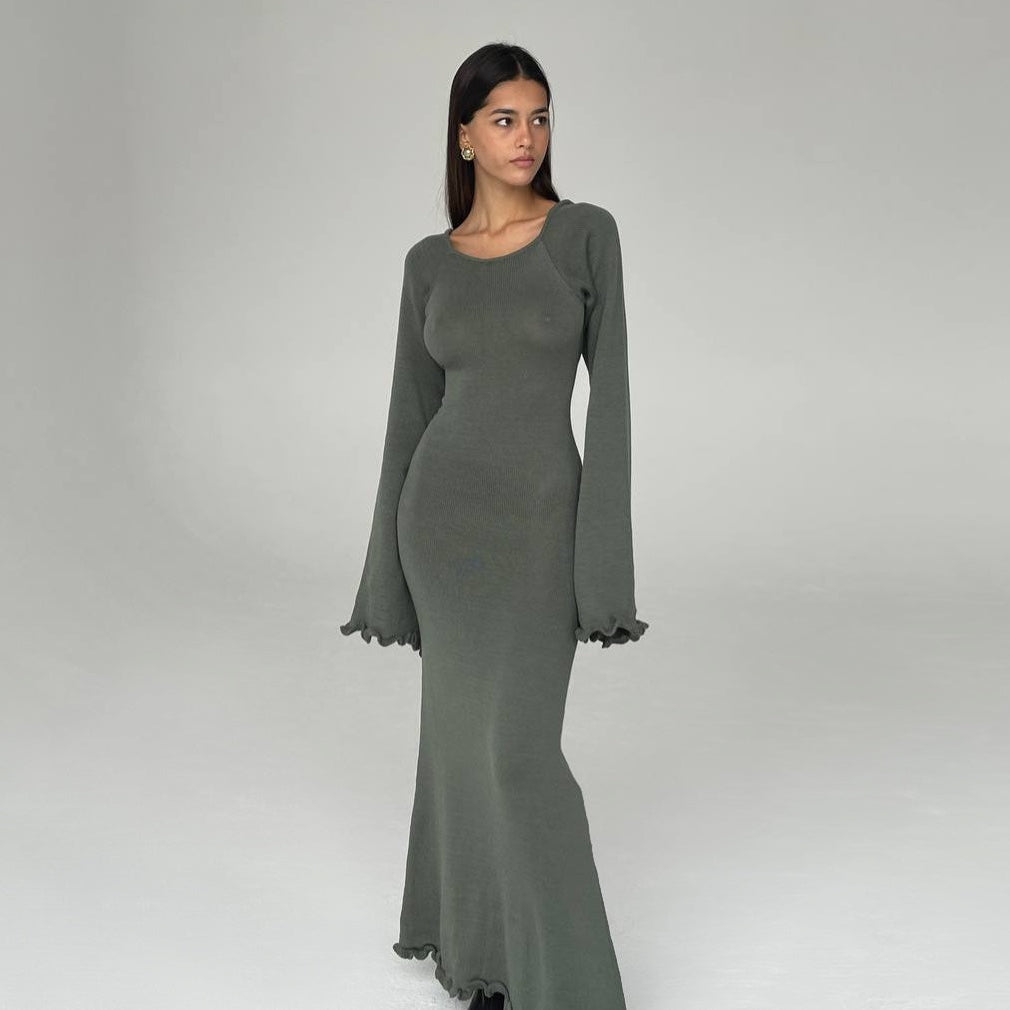Woman wearing a long green dress against a plain background