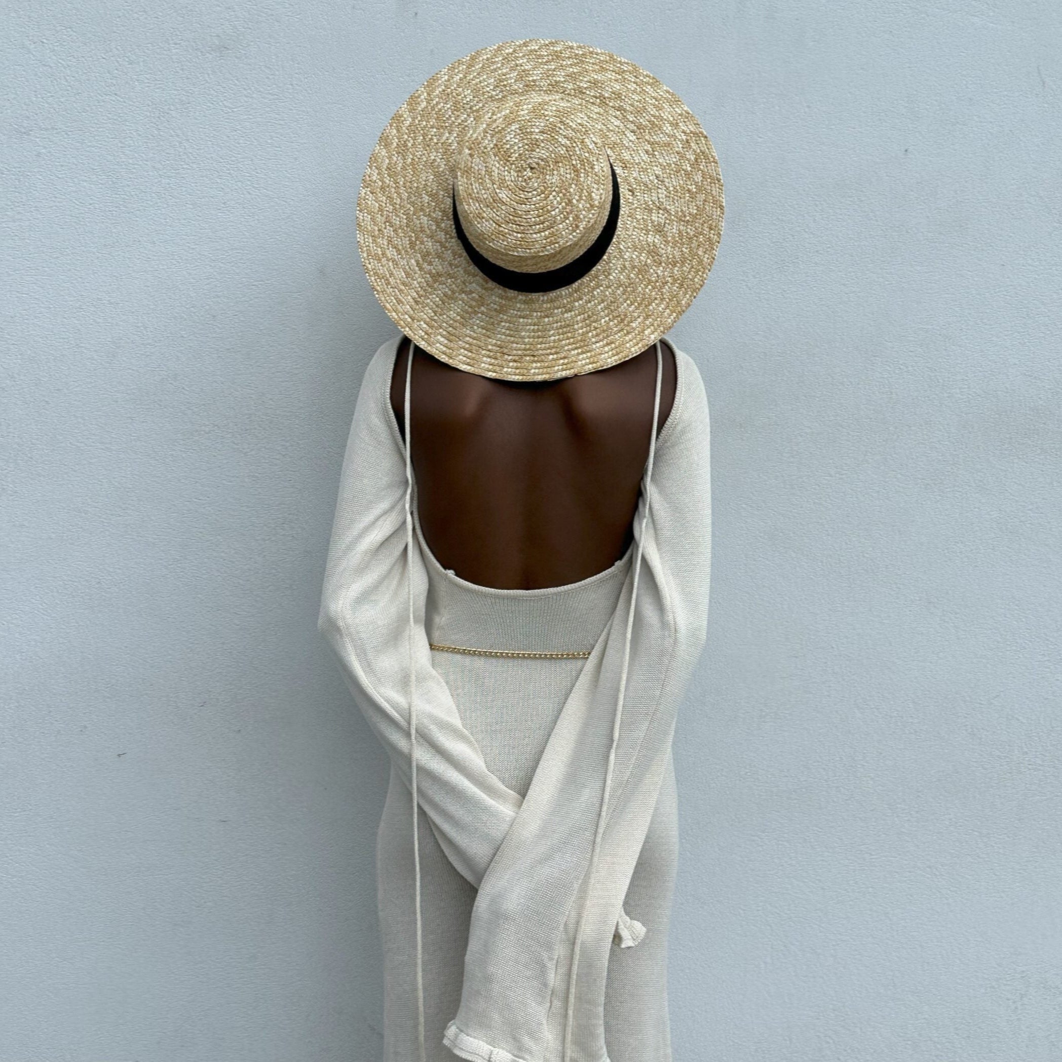 Person wearing a straw hat and white outfit against a light gray background