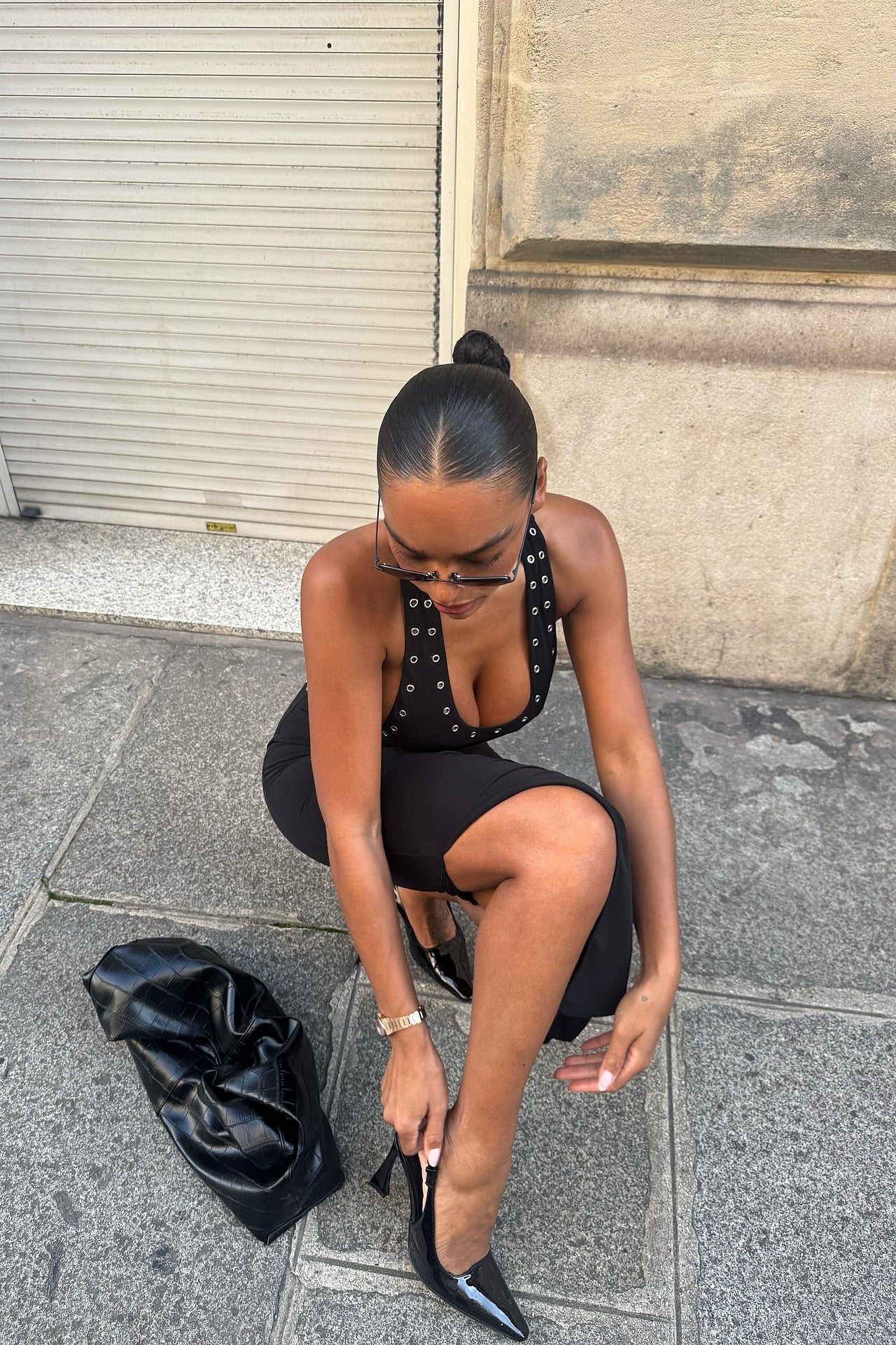 Black bodycon midi dress with eyelet trim straps and side slit, adjusting heel strap
