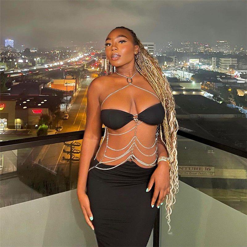 Woman in a black dress with chain details against a cityscape background