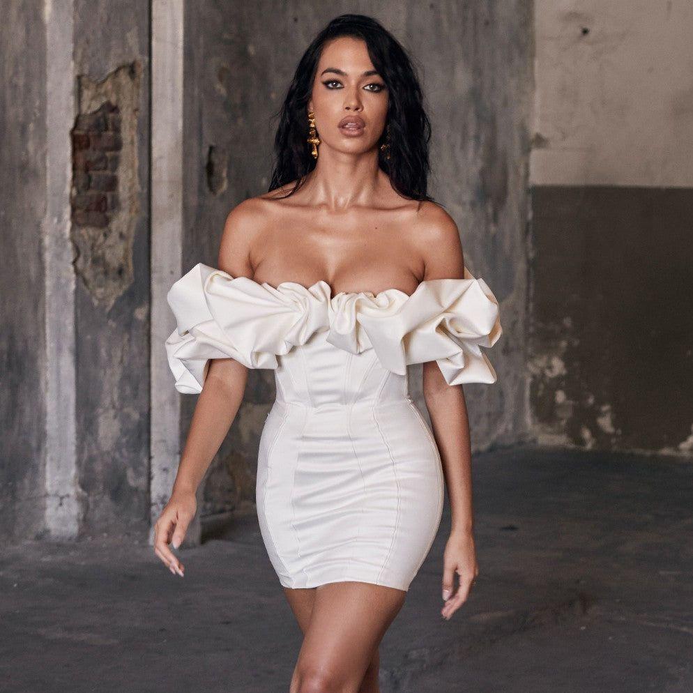 Woman wearing a white off-shoulder dress in an urban setting
