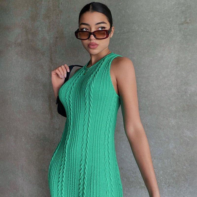 Woman wearing a green knitted dress against a gray background