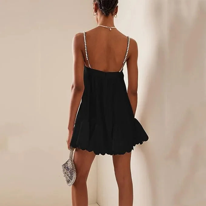 Black mini dress with pearl-accented straps, evening look.