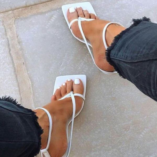 White sandals worn on feet with a neutral background