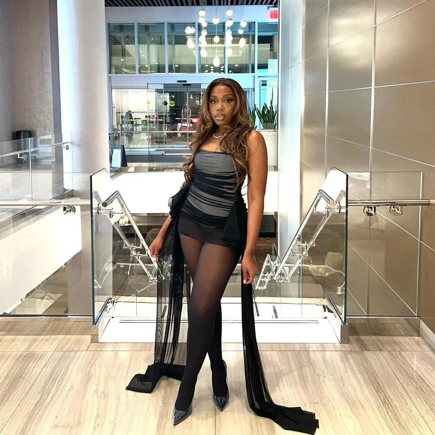 Black strapless mini dress with sheer mesh overlay and side sashes, sophisticated evening look.