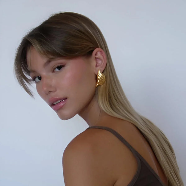 Gold leaf-shaped statement earrings, elegant accessory.