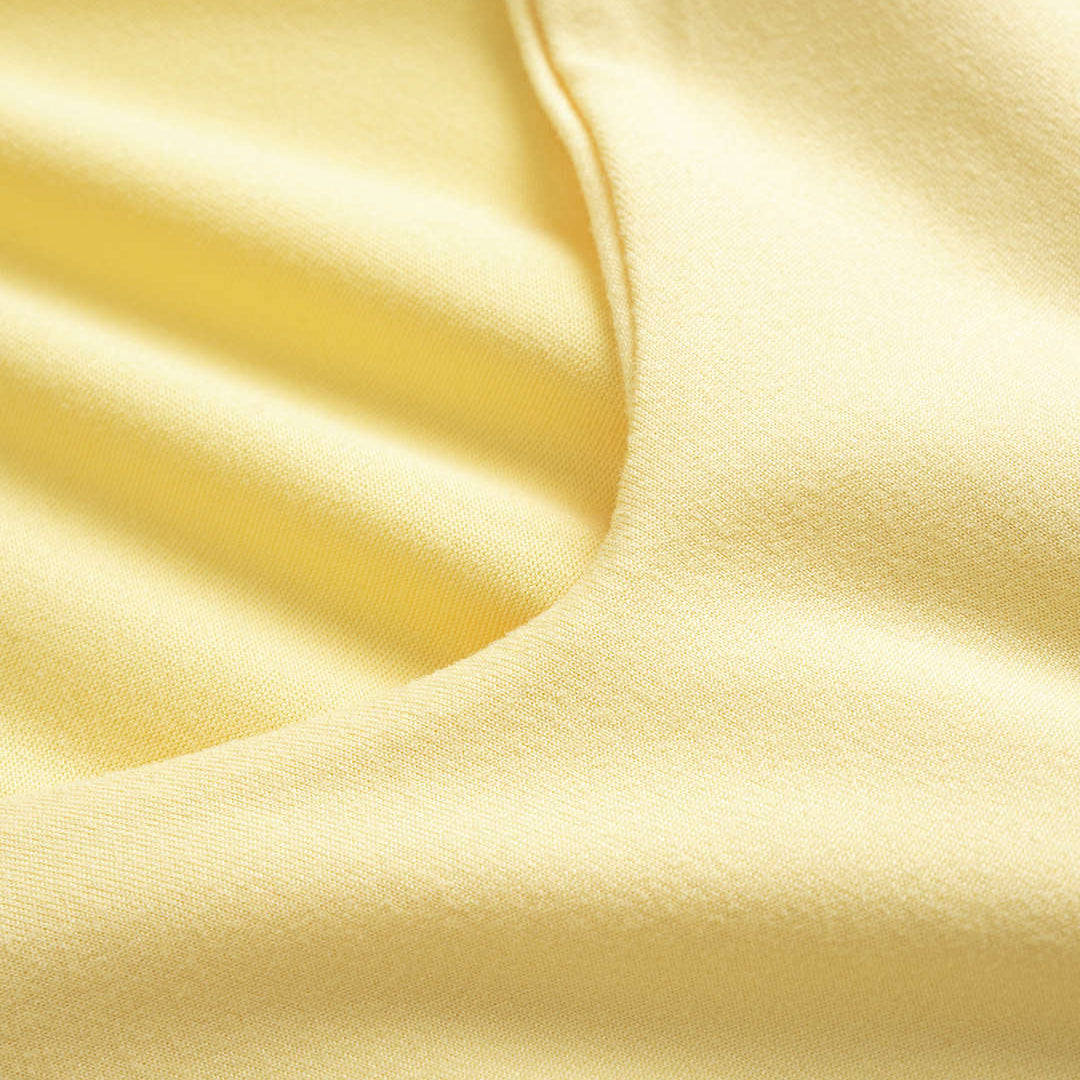 Close-up of smooth, light yellow fabric with folds