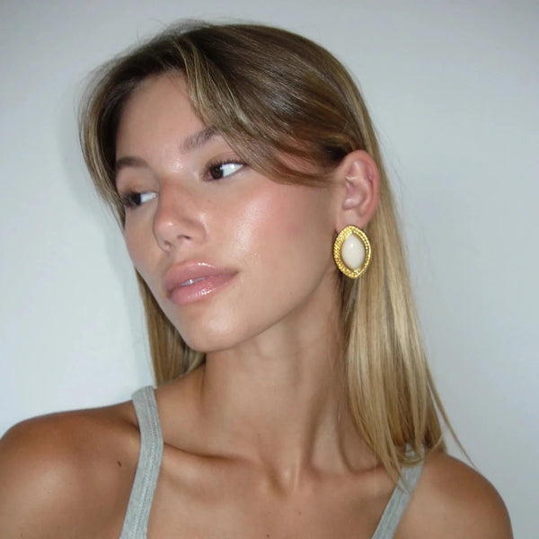 Gold statement earrings with oval off-white center, chic accessory.