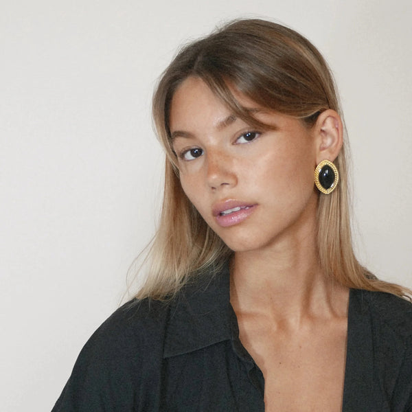 Gold statement earrings with black stone accents, elegant accessory.