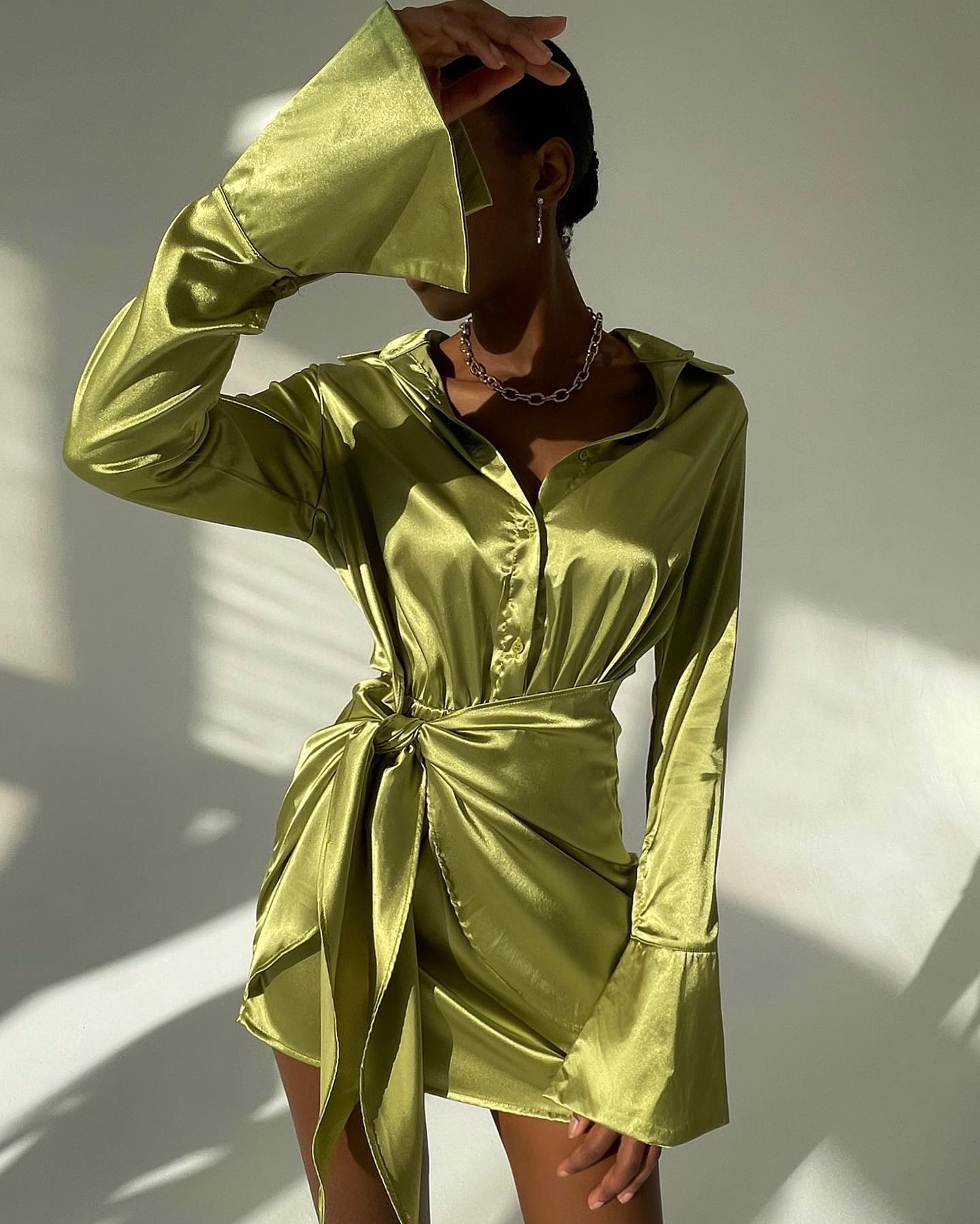 Jamaica green satin long sleeve mini dress with a tie waist and flared sleeves, styled effortlessly for a chic look.