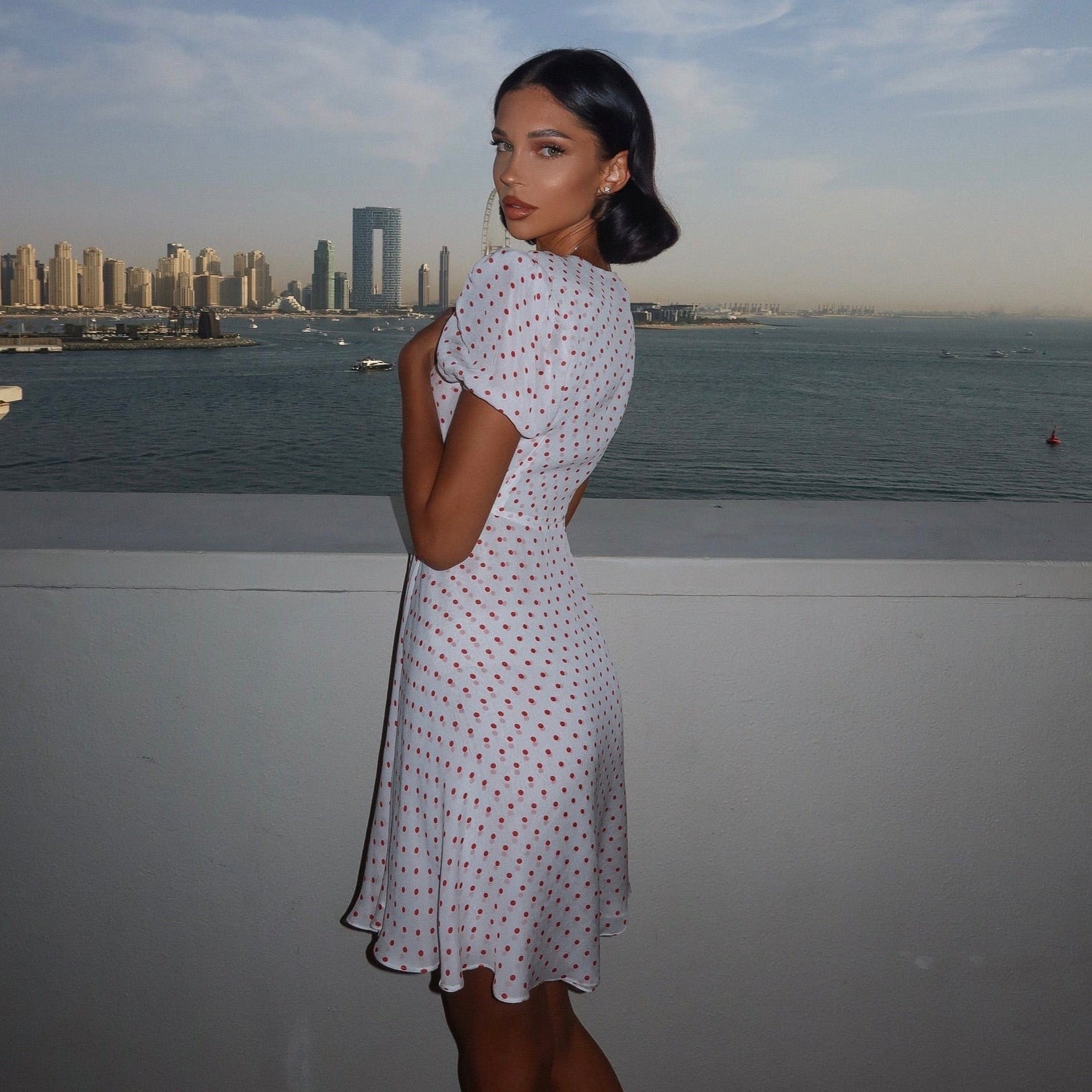 White polka dot vintage mini dress with short sleeves, fitted waist, and flared skirt, styled for a chic summer look.